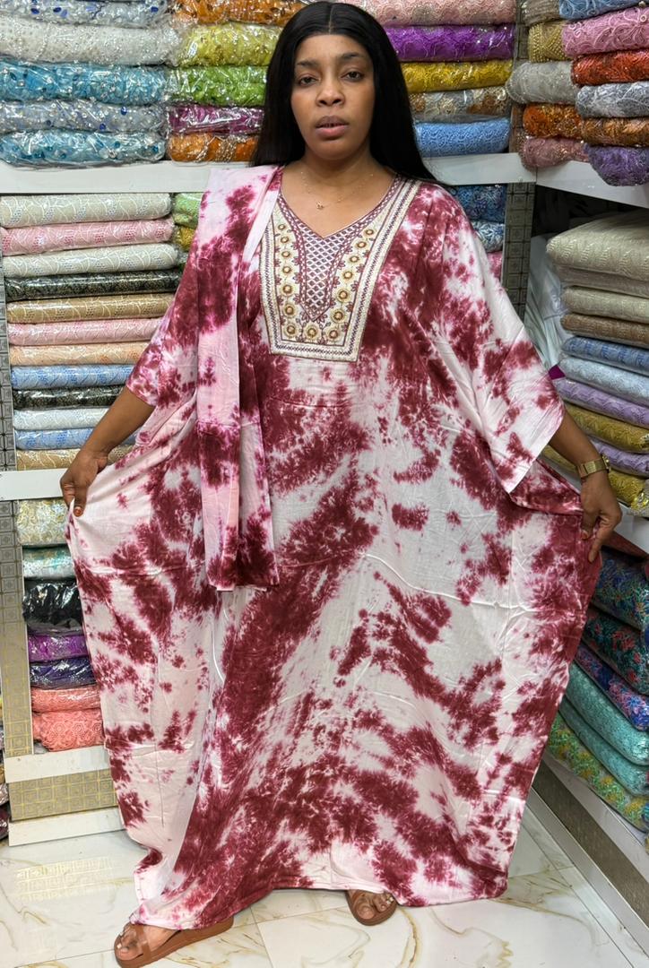 Style et Coupe : Il s'agit d'une robe de type caftan ou maxi robe, caractérisée par sa coupe fluide et généreuse qui offre confort et élégance. Elle est ici portée avec une capuche intégrée ou un voile assorti
 Le tissu présente des motifs tie-dye (teinture par nouage), souvent appelés Adire ou Thioup selon la région. Les couleurs dominantes sont le jaune orangé et le blanc, créant un effet visuel vibrant et artisanal.